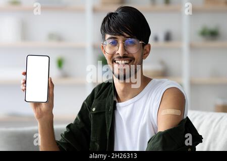 Uomo arabo felice che mostra smartphone con schermo vuoto Foto Stock