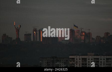 Non esclusiva: KYIV, UCRAINA - 20 OTTOBRE 2021 - il Monumento della Patria e la bandiera Ucraina che volano su un flagpole sono visti contro il residenziale Foto Stock