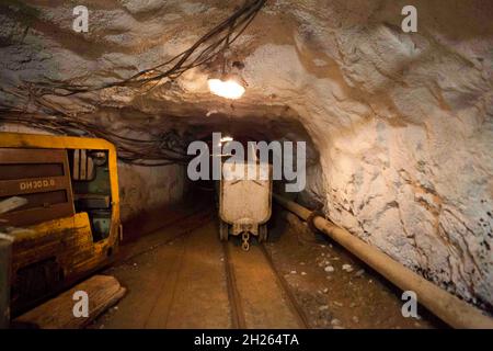 Hutch carrello con materie prime in piedi alla attività di estrazione mineraria. La produzione e il concetto di tecnologia. Tunnel con la stazione ferroviaria e la miniera di elettricità di cavi Foto Stock