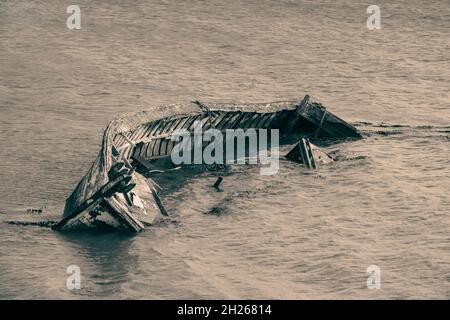 Abbandonato clinker costruito barca parzialmente sommerso su una riva del fiume Foto Stock