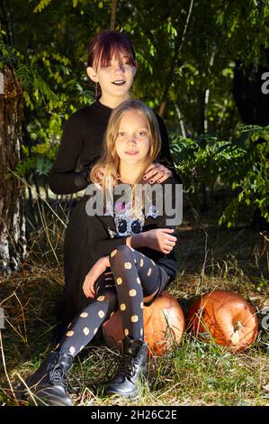 Due sorelle felici nella foresta di Halloween. Divertenti bambini in costumi di carnevale all'aperto a Halloween trick o delizia. Buon Halloween! Foto Stock