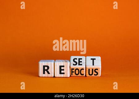 Rifocalizzazione e simbolo di reset. L'uomo d'affari girò i cubi e cambiò la parola 'focus' in 'set'. Bella tavola arancione, sfondo arancione. Business refo Foto Stock
