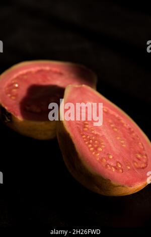 Colpo verticale di guava affettato in due pezzi. Foto Stock