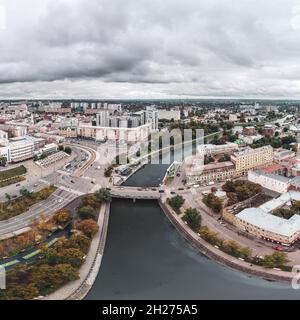 Vista panoramica aerea della città, ponte sul lungofiume autunnale di Lopan e Piazza Pavlivska con nuvole grigie pesanti a Kharkiv, Ucraina Foto Stock