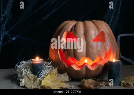 La foto di studio di Pumpkin, candele brucianti e spiderweb su sfondo scuro. Foto concettuale di Halloween. Foto Stock