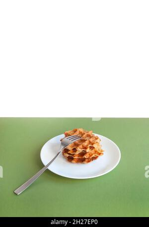I waffle belgi fatti in casa si accatastano con la forchetta al centro su un tavolo di colore verde. Foto Stock