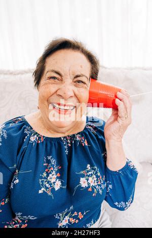 La donna anziana felice ride mentre ascolta un telefono a corda Foto Stock