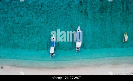 Foto ultralarga dal drone aereo in cima al basso della tradizionale barca da pesca in legno ancorata alla spiaggia di Lombok. Lombok, Indonesia, 20 ottobre 2021 Foto Stock