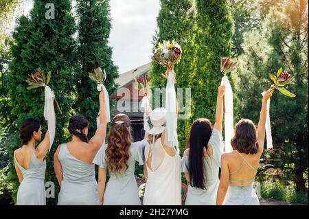 Bridesmaids in abiti blu e sposa con bei mazzi di fiori protea. Bellissimo matrimonio di lusso blog concetto. Matrimonio estivo. Foto Stock