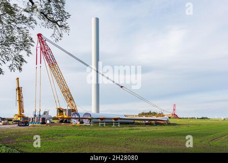 Cantiere preparato per l'assemblaggio di un parco eolico. Gru a vista, gru gialla e gondola ripiegata, palo Foto Stock