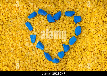 Ciottoli a forma di cuore blu su sfondo giallo, concetto giorno valentine. Simbolo d'amore nei colori della bandiera nazionale dell'Ucraina Foto Stock