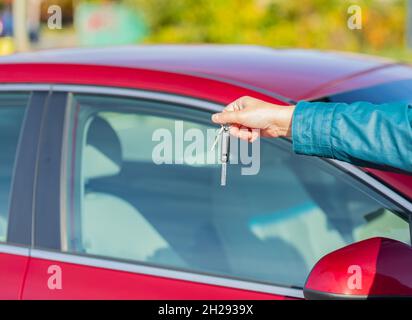 Chiavi per l'auto. Le chiavi di mano femmina di un'auto rossa Foto Stock