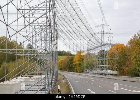 Un grande ponteggio con una rete di sicurezza per proteggere il traffico stradale a causa del lavoro su una linea ad alta tensione e sui tralicci di elettricità. Foto Stock