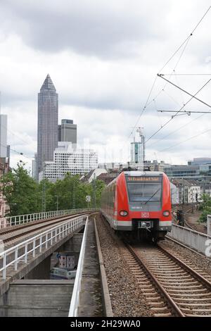 FRANCOFORTE AM mai, GERMANIA - 10 giugno 2019: Un primo piano di un treno che guida di fronte ai grattacieli sotto il cielo nuvoloso Foto Stock