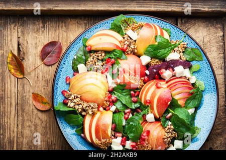 Insalata fresca autunnale con mela, melograno, farinata d'avena e formaggio feta su tavola rustica in legno Foto Stock