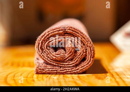 Tovagliolo marrone in microfibra a tre strati arrotolato su una superficie di legno Foto Stock