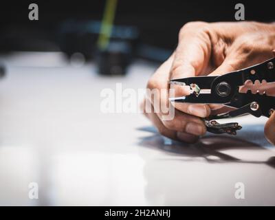 Il closeup a mano di un elettricista utilizza pinze spelafili elettriche in applicazioni industriali. Foto Stock