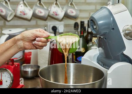 Lo chef versa la birra frizzante dalla siviera in una ciotola. Foto Stock