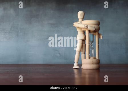 Gestione del tempo, non perdere tempo concetto. Figura umana in legno abbraccia il vetro smerigliato. Spazio di copia per il testo Foto Stock