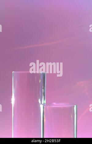 due podi in vetro trasparente su sfondo rosa pastello Foto Stock
