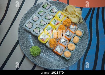 Un grande set di diversi sushi panini piccanti caldi con salmone, formaggio cremoso e anguilla è su un pannello di legno. Foto Stock