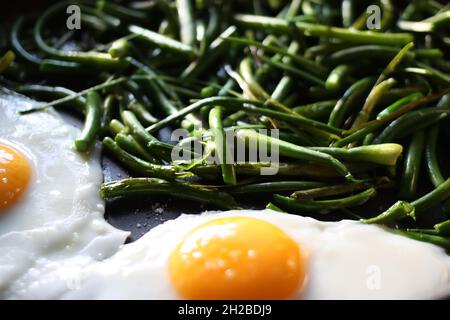 Uova fritte con fagioli verdi sulla padella da vicino Foto Stock