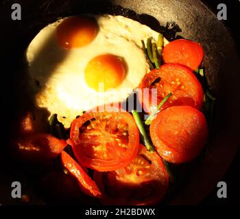 Uova fritte in stile country con pomodori rossi freschi Foto Stock