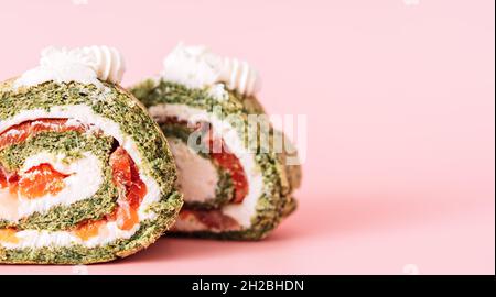 Due spicchi di rotolo con spinaci e pesce rosso su sfondo rosa Foto Stock