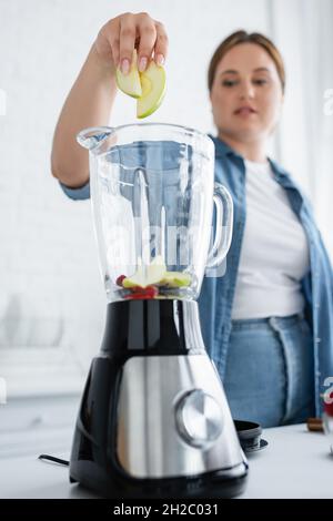 Donna sfocata con troppo peso mettere la frutta nel frullatore Foto Stock