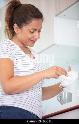 bella ragazza versa l'acqua dal bollitore in cucina Foto Stock