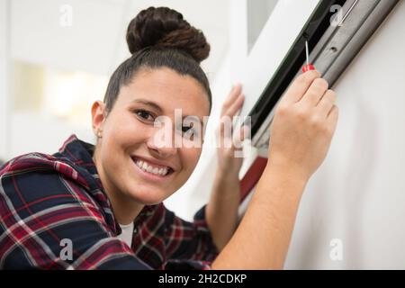 Donna installazione di persiane con cacciavite Foto Stock