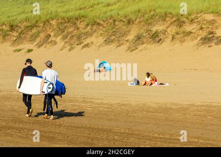 Surfers sulla spiaggia di sabbia a Woolacombe sulla costa nord del Devon Inghilterra Regno Unito vicino al South West Coast Path. Foto Stock