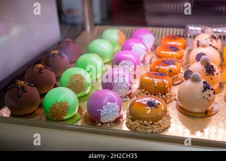 Set di torte di mousse multicolore con smalto lucido a specchio sul banco del mercato alimentare Foto Stock