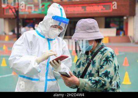 (211021) -- LANZHOU, 21 ottobre 2021 (Xinhua) -- un operatore medico registra un residente per il test dell'acido nucleico COVID-19 in un sito di test temporaneo presso una scuola elementare di Lanzhou, capitale della provincia di Gansu della Cina nordoccidentale, 21 ottobre 2021. Lanzhou ha sospeso le lezioni di persona per gli asili locali, le scuole primarie e superiori e gli istituti di formazione fuori dal campus a partire da giovedì per il controllo COVID-19. Le autorità sanitarie avevano raccolto 11,326 campioni per il test degli acidi nucleici da nove scuole di Lanzhou, con tutti i campioni test negativi, ha detto l'ufficio informazioni del governo provinciale Foto Stock