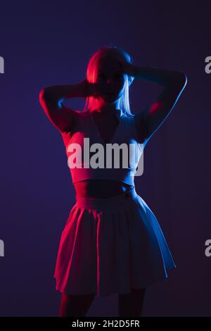 Ritratto di una giovane donna canadese in abbigliamento sportivo in posa sotto le luci blu e rosse in uno studio scuro Foto Stock