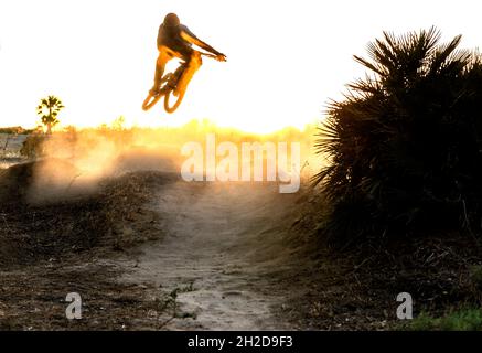 Giovane mountain bike salta in un tramonto ventoso e polveroso in Spagna Foto Stock