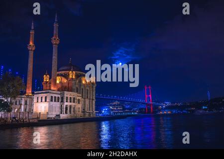 Moschea di Ortaköy e Ponte sul Bosforo durante l'ora blu, luna piena e cielo notte blu. Una delle località più popolari di Istanbul, Turchia. Foto Stock