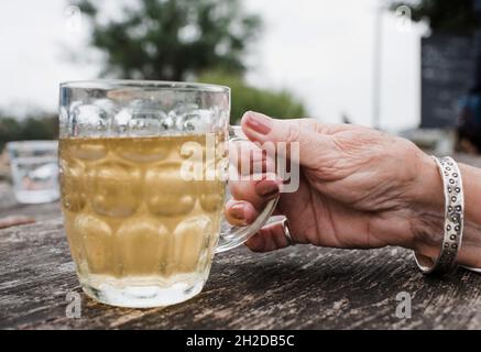 mano della donna che tiene un bicchiere di pinta con sidro all'esterno Foto Stock