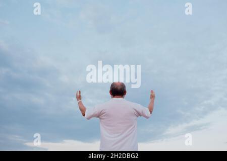 Uomo anziano con le mani in su. L'uomo adulta dell'asle prega in cielo. Foto Stock