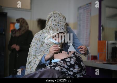 Rafah. 21 ottobre 2021. Una donna palestinese impara le abilità di trucco durante un addestramento di cura di bellezza al centro affari delle donne nella città meridionale della striscia di Gaza di Rafah, 21 ottobre 2021. Il centro ha recentemente iniziato a fornire corsi di bellezza per aiutare le donne delle famiglie povere a prepararsi al mercato del lavoro. Credit: Khaled Omar/Xinhua/Alamy Live News Foto Stock