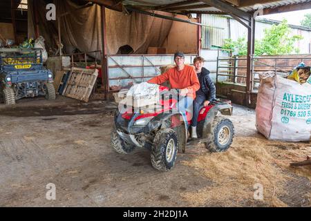 I ragazzi della fattoria che cavalcano una Honda quad bike, High Bickington, Devon, Inghilterra, Regno Unito. Foto Stock