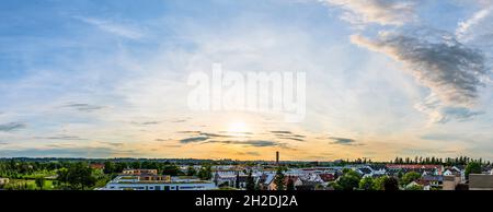 Cielo serale con sole basso su una città Foto Stock