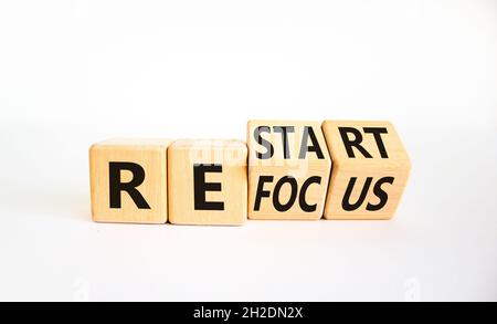 Simbolo di rifocalizzazione e riavvio. L'uomo d'affari girò i cubi e cambiò la parola 'focus' in 'restart'. Bella tavola bianca, sfondo bianco. Business re Foto Stock