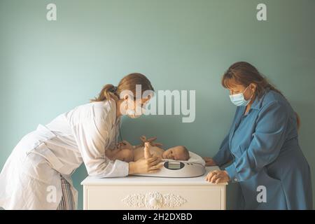 Bambino su scala di peso al medico Foto Stock