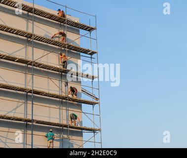 UZHGOROD, UCRAINA - 16 settembre 2021: Operai di costruzione che mettono l'intonaco decorativo sull'esterno della casa. Isolamento termico della facciata e lavori di pittura Foto Stock