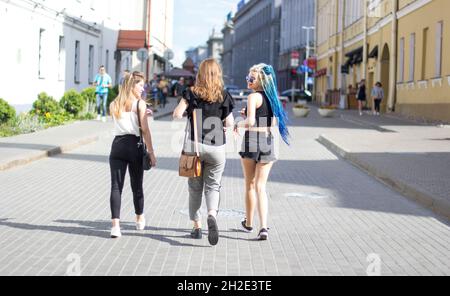 Una giovane ragazza con lucchetti blu e occhiali eleganti con due amici cammina nel centro di Minsk lungo Engels Street l'8 luglio 2018 Foto Stock