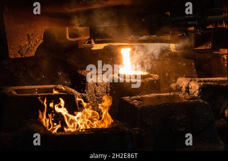 Il metallo liquido viene versato in stampi di acciaio dalla siviera metallurgica. Foto Stock