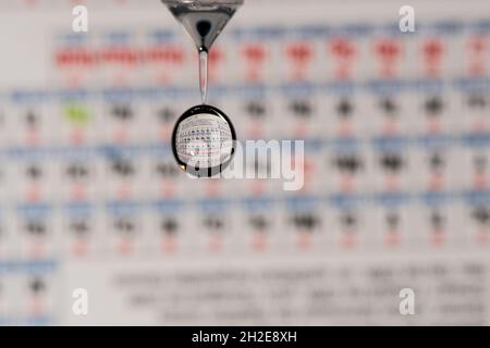rifrazione periodica degli elementi del piano d'esame in una goccia d'acqua in caduta Foto Stock