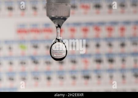 rifrazione periodica degli elementi del piano d'esame in una goccia d'acqua in caduta Foto Stock