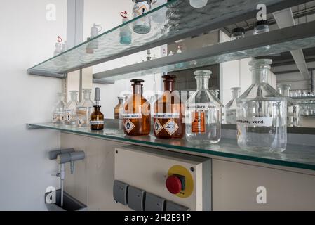 luogo di lavoro in un laboratorio chimico con bottiglie di acidi e basi Foto Stock